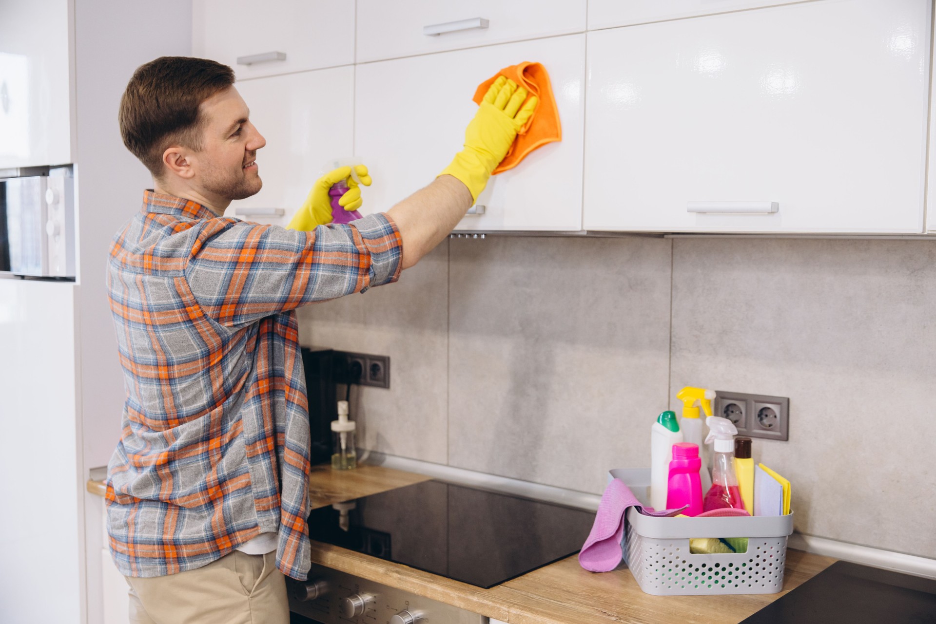 Man Cleaning Kitchen Cabinets with Detergent and Microfiber Cloth