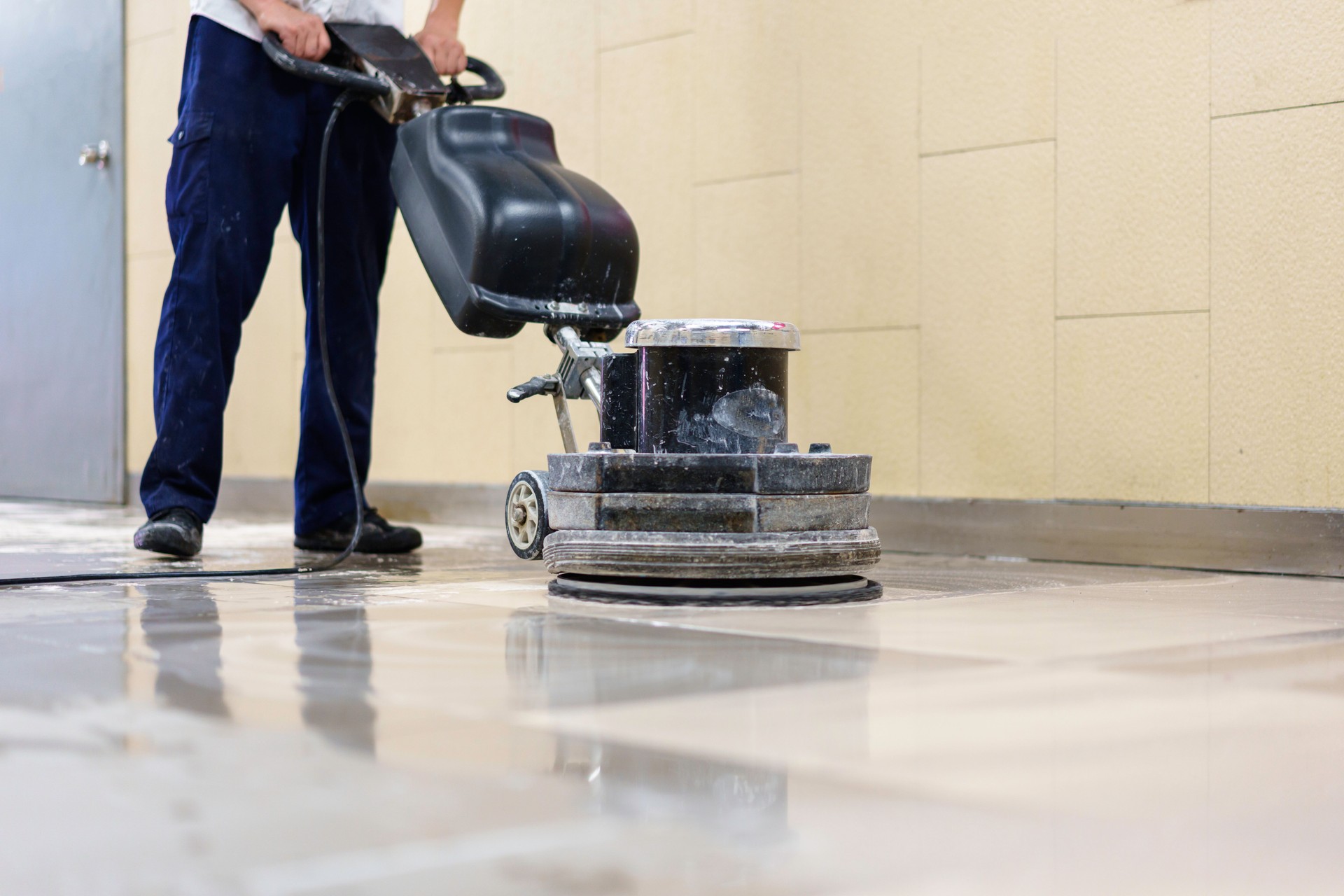 A worker is using a floor scrubber to clean the floor.